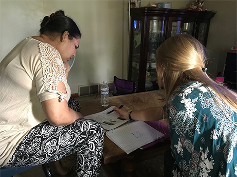 Two women gathered around a table studying notes on a paper.